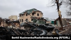 Уништен руски тенк пред гранатирана куќа на улицата Вокзална, фотографиран на 1 март 2022 година