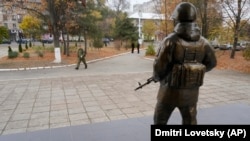 Un militar trece pe lângă statuia unui soldat, lângă sediul Grupului Operațional al Forțelor Ruse din Tiraspol.
