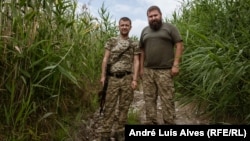Soldații ucraineni Rostislav (stânga) și Oleksandr patrulează pe malul râului în Prîmorske.