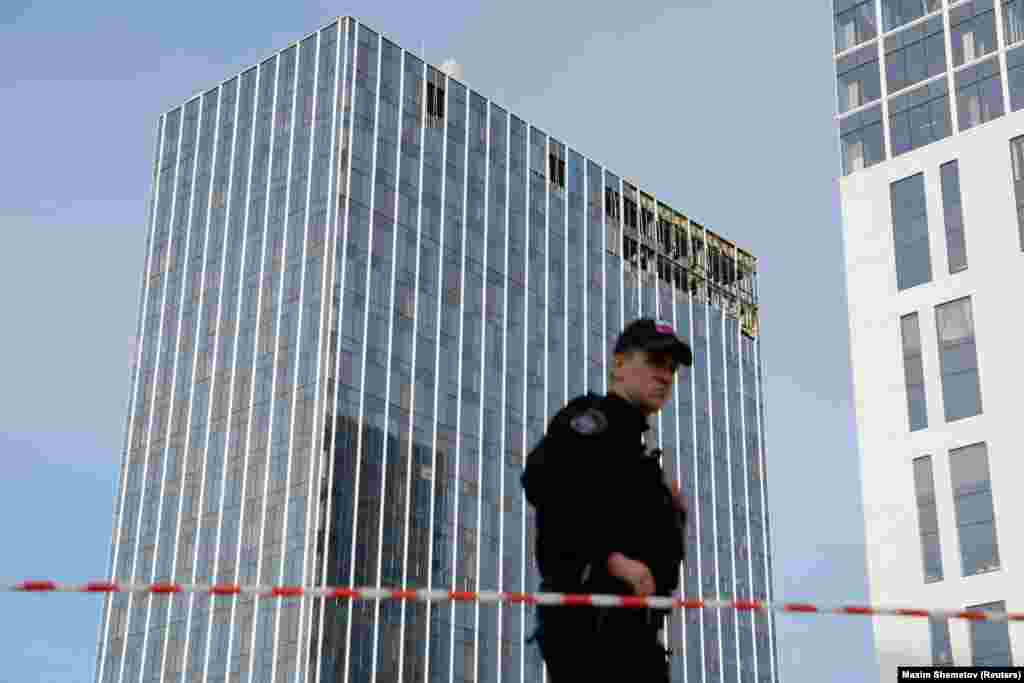 Un membru al serviciilor de securitate de pază lângă una dintre clădirile avariate din Moscova. Agenția de presă TASS a raportat că o dronă s-a prăbușit în Komsomolski Prospekt, în apropierea ministerului, în timp ce o alta a lovit un centru de afaceri de pe strada Lihaceva, lângă una dintre principalele șosele de centură ale Moscovei.