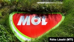 A természetközeliséget szimbolizálva növények között a Mol céglogója az egyik, napelemekkel is felszerelt üzemanyagtöltő állomásán Budapesten 2022. július 17-én