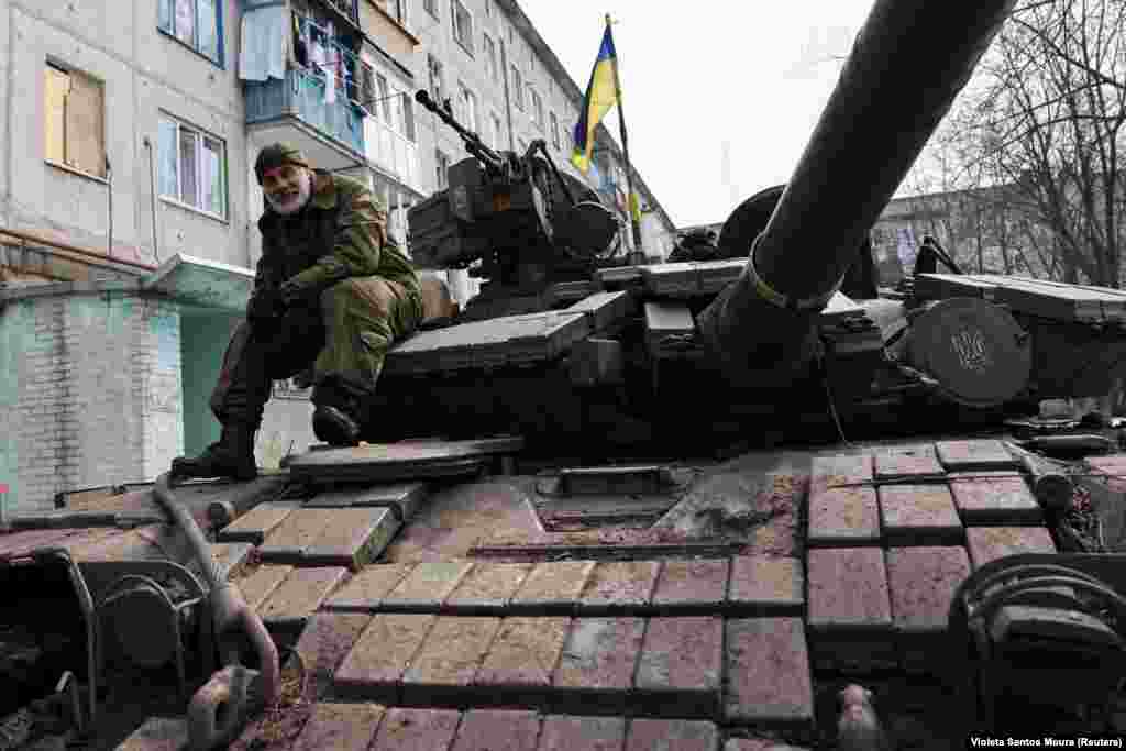 Украински војник седи на тенк во станбена област во близина на Бахмут. Во градот сеуште се водат борби, иако руските сили тврдат дека го освоиле.