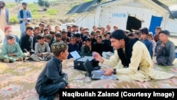 د خوست اوسېدونکی نقیب الله ځلان په ښوونځي کې د شاملولو په هدف د یو ماشوم ته د وړیا عکس اخیستلو پر مهال.