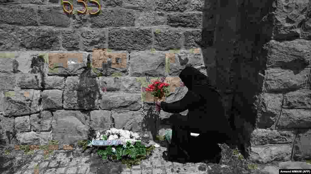 Srpska pravoslavna časna sestra polaže cveće na spomenik. 