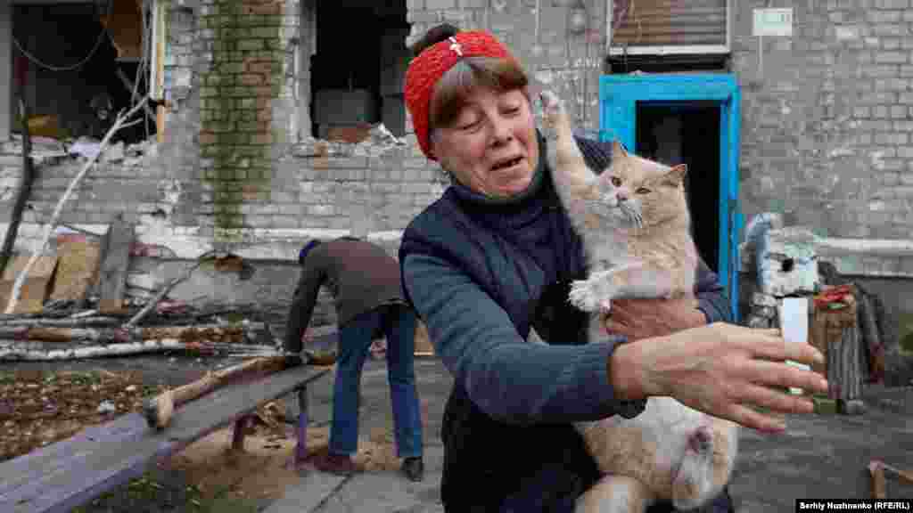 Местната жителка Рита държи котка, докато нейната съседка Раиса реже дърва. Малкото останали цивилни в Авдиивка търсят убежища от постоянните обстрели в мазетата на разрушените сгради. 