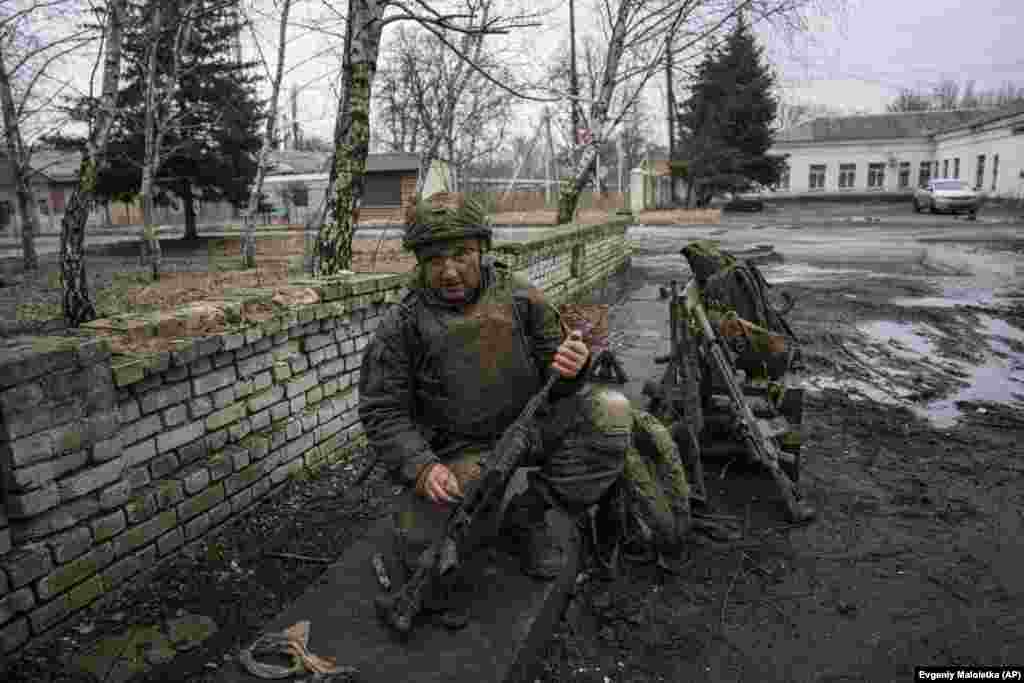 A Ukrainian soldier cleans mud from his gun after returning from the fighting in Bakhmut. 