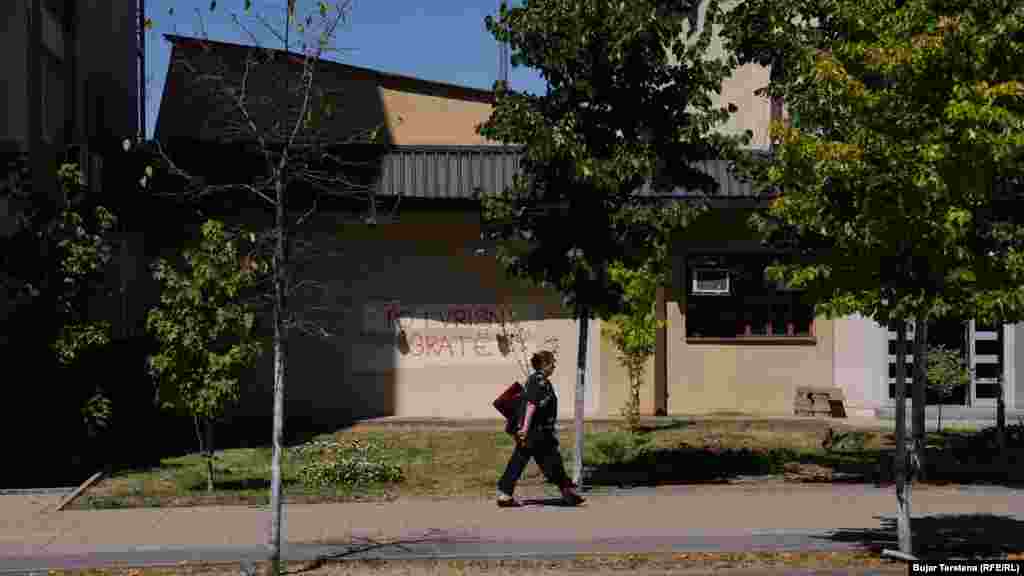 Një grua kalon pranë një grafiti kundër femicidit – “Po vrisni gra”, i shkruar në ndërtesën e Policisë së Kosovës, Prishtinë, Kosovë, 7 gusht 2024.