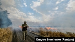 Украински военен върви до горящо поле с пшеница в Донецк на 17 юли.