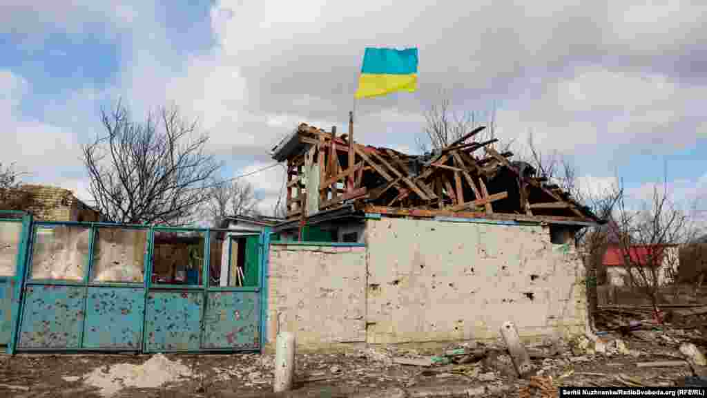 Селище Лук&#39;янівка одразу після звільнення від російських окупантів. Над зруйнованою цивільною будівлею та посіченим кулями двором майорить прапор України. Київщина. Кінець березня 2022 року.