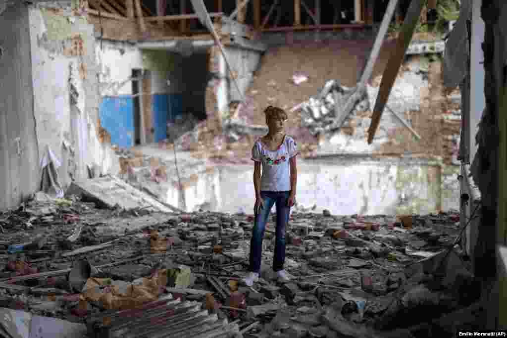 Sofia Klișia, în vârstă de 12 ani, se află printre dărâmăturile fostei sale săli de clasă, în aceeași poziție în care se afla pupitrul ei înainte ca liceul Mykhailo-Kotsyubynske să fie bombardat de forțele rusești pe 4 martie. „Mi-e frică să stau în partea distrusă a clasei în care am studiat cândva”, a spus ea.