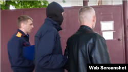 Captură de ecran dintr-un reportaj al organelor de forță de la Tiraspol despre atacul lui Alexandr Dimov asupra comisariatului militar din regiune. În imagine, acesta este escortat spre comisariat pentru a explica cum a acționat.