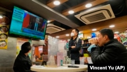 Gosti restorana u Hongkongu gledaju program o invaziji ruskih trupa na Ukrajinu, 24. februar 2022.
