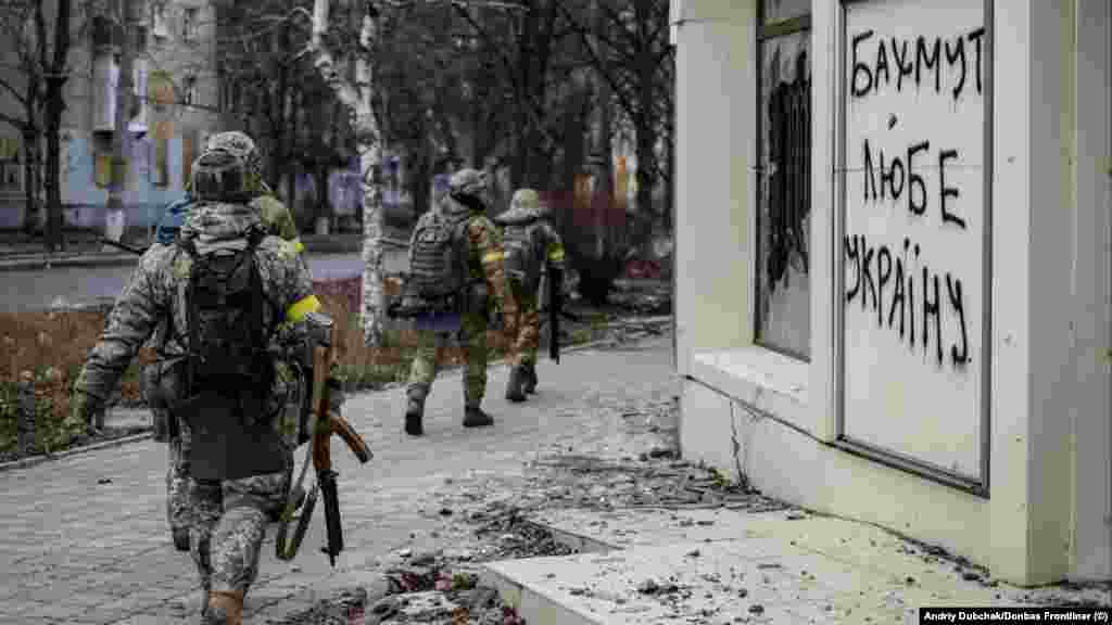 Militari ucraineni trec pe lângă un mesaj scris pe un zid: „Bahmut iubește Ucraina”, 18 decembrie. Rusia și Ucraina aruncă echipament și trupe în lupta pentru Bahmut, oraș în regiunea Donețk, estul Ucrainei, care are o importanță militară minoră, dar e revendicat ca simbol de ambele tabere. 