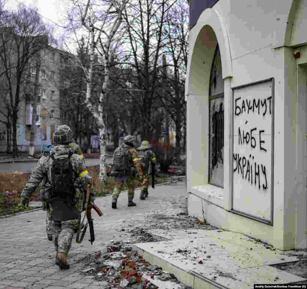 Украински војници поминуваат покрај графити на кои пишува „Бахмут ја сака Украина“ на 18 декември. И Русија и Украина во моментов внесуваат луѓе и материјал во борбата за Бахмут, град во регионот Донбас во источна Украина кој има релативно мало воено значење, но стана жестоко оспоруван симбол за двете страни.