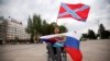 Мужчина держит флаг так называемой «Новороссии» (сверху) и России (внизу) во время митинга на площади Ленина в оккупированном Донецке, 13 июля 2014 года