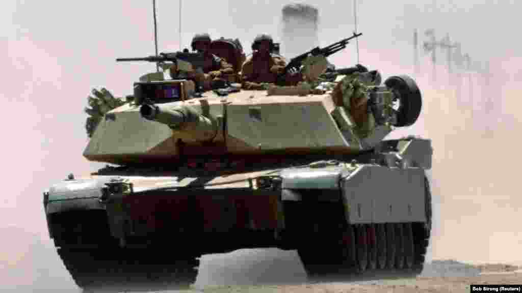 Un tanc M1A1 Abrams al pușcașilor marini americani rulează cu viteză pe o autostradă în apropiere de un punct de control militar de la Fallujah, 1 iulie 2004. Se crede că armata Statelor Unite are în dotare 2.509 de tancuri Abrams în diferite versiuni, și încă 3.700 în depozite.