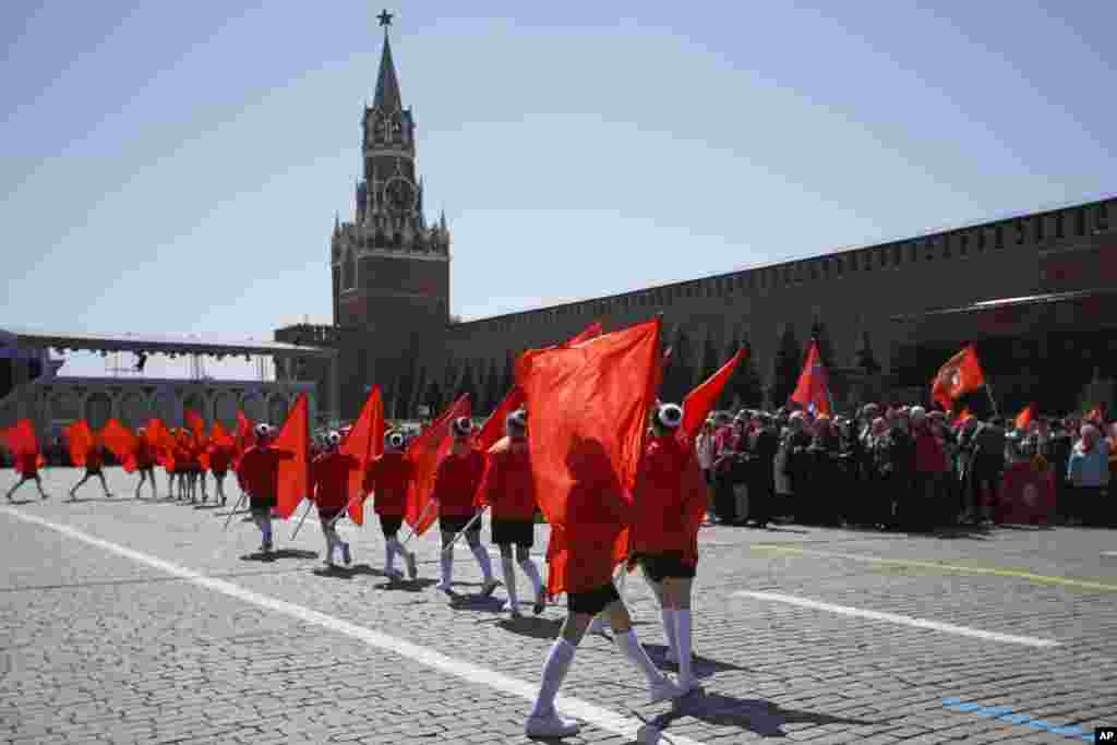 Children march with blank red flags in front of the Kremlin's Spassky Tower. The Communist Party initiative comes as children in schools across Russia have been coerced into showing "support" for the invasion of Ukraine, often without the knowledge of parents.