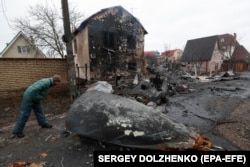 Мешканець Київської області дивиться на уламки російського військового літака, збитого українською проти-повітряної обороною. 25 лютого 2022 року