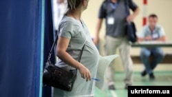 Вагітна жінка виходить з кабінки для голосування на виборах до Верховної Ради. Харків, 21 липня 2019