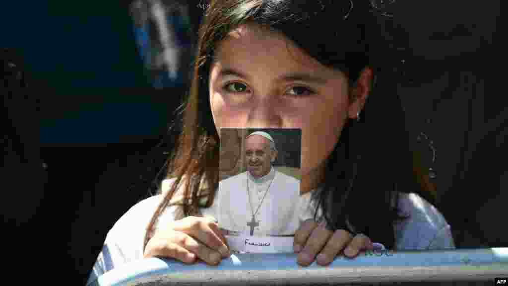 O tânără credincioasă ține o fotografie a răposatului Papă Francisc în timp ce așteaptă ceremonia funerară a răposatului Papă Francisc.