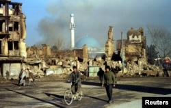 Снимка от 1994 г. показва афганистанци, които минават покрай сгради в Кабул, разрушени по време на гражданската война в страната.