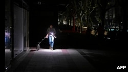 O femeie își luminează calea cu telefonul mobil în timpul penei de curent în Peninsula Iberică, Vigo, 28 aprilie 2025

