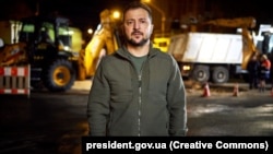 Președintele Ucrainei, Volodimir Zelenski, și-a transmis mesajul de luni seară din stradă. În spatele lui, echipele de intervenție reparau rețeaua electrică avariată în atacurile cu rachetă lansate dimineață de Rusia.