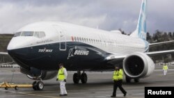 Ground crew members escort a Boeing 737 MAX as it returns from a flight test at Boeing Field in Seattle, Washington, in January 2016.