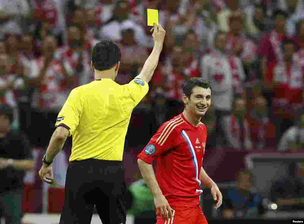 Russia's Alan Dzagoev (right) reacts as referee Wolfgang Stark of Germany shows him the yellow card during the match against Poland in Warsaw.