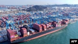 Macarale descarcă containere de pe o navă într-un port din Qingdao, în provincia Shandong din estul Chinei, aprilie 2025.