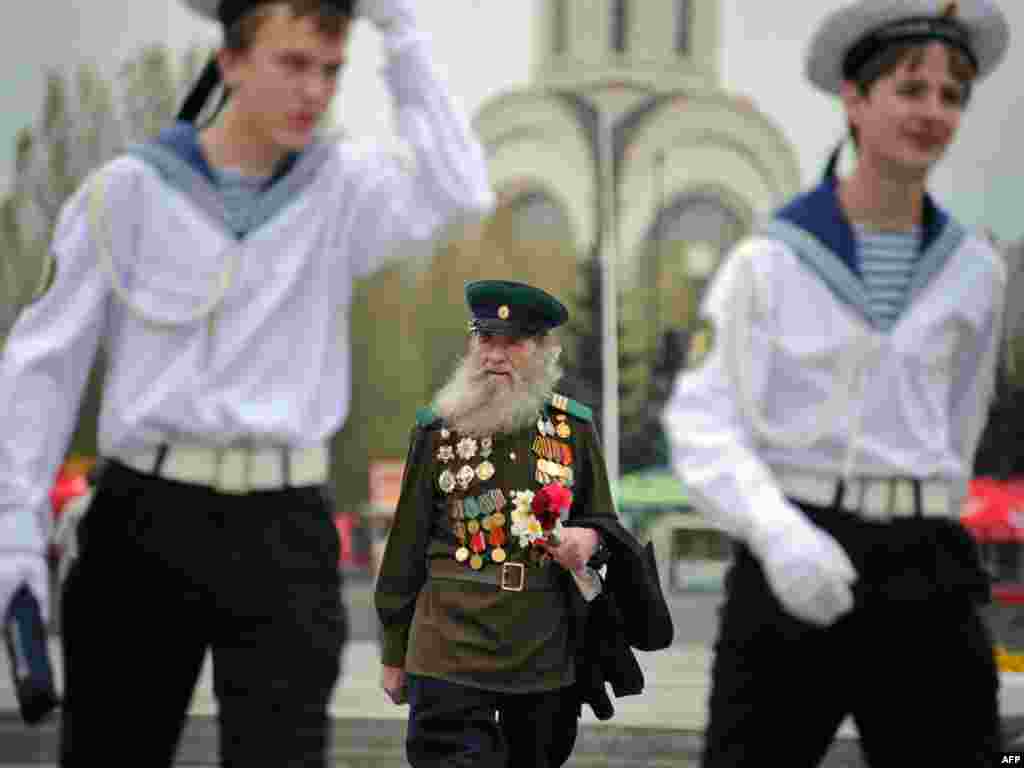 День Победы, порохом пропах... - Российский ветеран войны следует за молодыми моряками в г.Москве. Фото AFP.