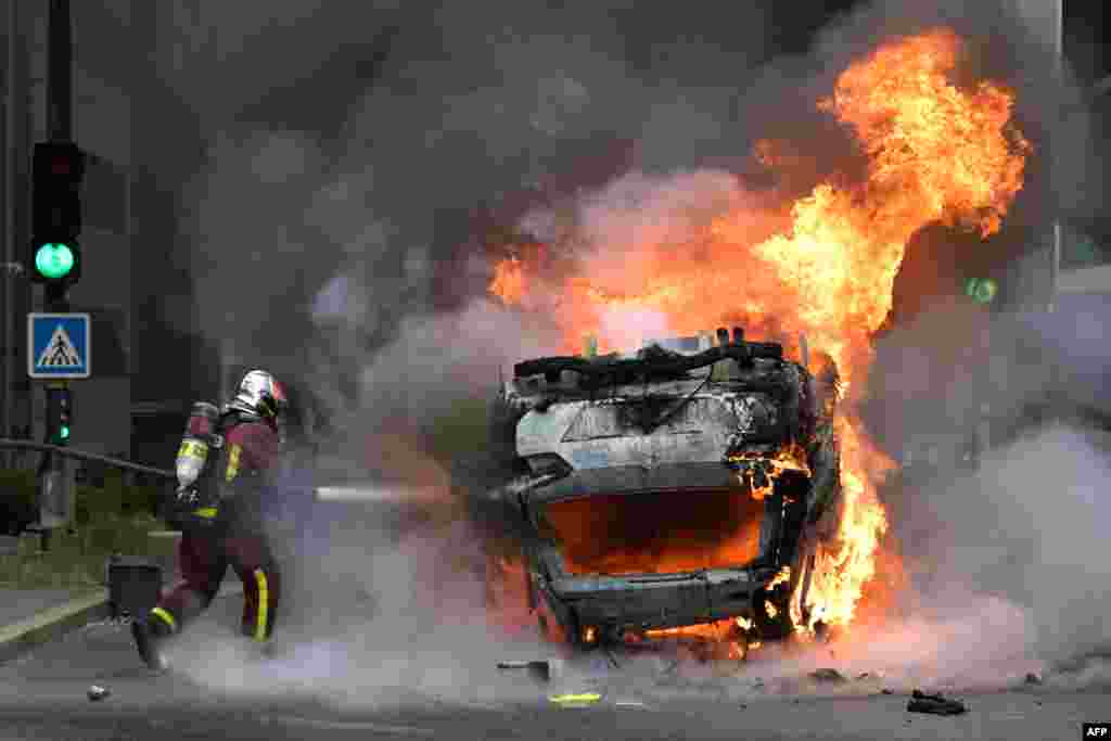 Vatrogasac gasi zapaljeni automobil u pariškom predgrađu Nanterre, 29. juna 2023.