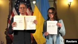 Američki ministar financija Scott Bessent (lijevo) i Yulia Svyrydenko, ukrajinska ministrica ekonomije i zamjenica premijera poziraju fotografima pokazujući ugovor o mineralima koji su potpisali u Washingtonu 30. aprila.