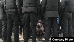 Айзат Абильсеит в окружении полицейского СОБРа в Алматы в день выборов в парламент.