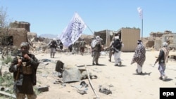 FILE: Taliban militants wave their flag patrol in a rural district of central Afghanistan in May 2017.