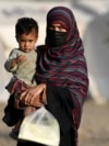 An Afghan woman holds a child as she arrives from Pakistan at a makeshift camp near the Afghanistan-Pakistan Torkham border in Nangarhar Province on April 20.