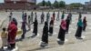 People stand in designated areas marked on the ground to maintain social distance as they receive free food from volunteers of Chhipa Welfare Association during a government-imposed nationwide lockdown in Karachi on March 27.
