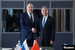 Ministrul rus de externe, Serghei Lavrov, dă mâna cu ministrul chinez de externe, Wang Yi, în timpul unei întâlniri desfășurate în marja summitului Grupului celor 20 (G20) de la Johannesburg, Africa de Sud, pe 20 februarie 2025.