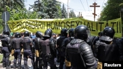 Polițiști în fața unui banner anti-LGBT la Chișinău, la 16 iunie 2024.