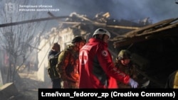 În imagine, echipe de salvare ucrainene, intervenind pentru evacuarea persoanelor, la Zaporojie, vineri noapte. 
