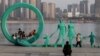 5 ianuarie, Wuhan - Oameni care fac poze lângă o statuie recent renovată, ce reprezintă o familie cu trei copii, în parcul Hankou (AFP/CHINA OUT)