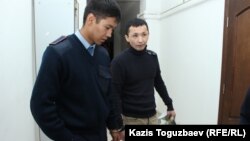 Полиция Әсет Нұржаубайды қолына кісен салып сотқа алып келе жатыр. Алматы, 26 қыркүйек 2018 жыл.