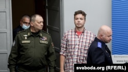 Начальнік камандаваньня ВПС і СПА Узброеных сіл Беларусі Ігар Голуб (зьлева), Раман Пратасевіч (у цэнтры) і старшыня Сьледчага камітэта Беларусі Дзьмітры Гара (справа) заходзяць у прэс-цэнтр перад брыфінгам. Менск, 14 чэрвеня 2021