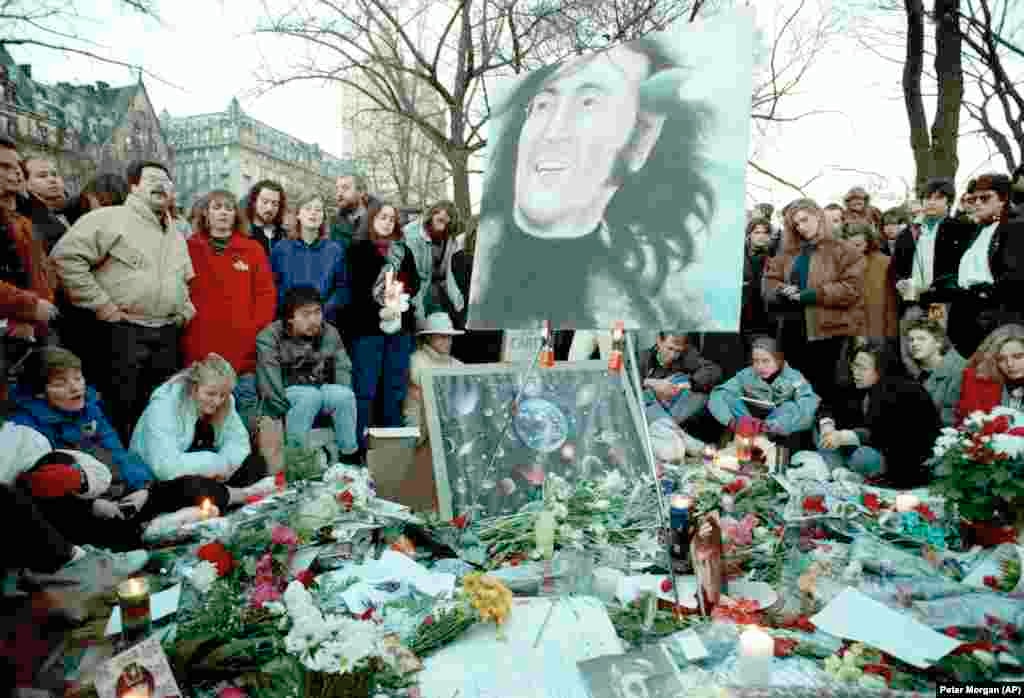 Люди собрались на «Strawberry Fields» в Центральном парке в десятую годовщину со дня убийства Джона Леннона, 8 декабря 1990 года. На заднем плане – многоквартирный дом «Дакота», где Леннон жил со своей семьей