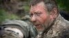 Un soldat ucrainean primește primul ajutor pe un drum în apropiere de Bahmut, la 11 mai.