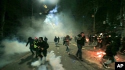 Demonstranți fugind de polițiști la Tbilisi în noaptea de sâmbătă spre duminică.