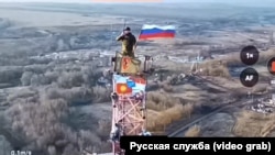 Un soldat rus ridică steagul Rusiei deasupra localității Malaia Loknia, în regiunea Kursk.