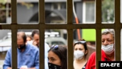 Луѓе со маски се штитат против Ковид-19. Илустрација.