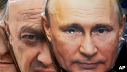 Санкт-Петербургдагы зер дүкөнүнүн терезесиндеги Орусиянын президенти Владимир Путиндин (оңдо) жана "Вагнер" тобунун жетекчиси Евгений Пригожиндин сүрөттөрү түшүрүлгөн бет каптар. 2023-жыл, 4-июнь 