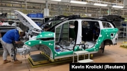 Angajați care lucrează la un vehicul electric (EV) de pe o linie de producție a unei fabrici care aparține Jiangling Group Electric Vehicle in Nanchang, provicia Jiangxi, China.